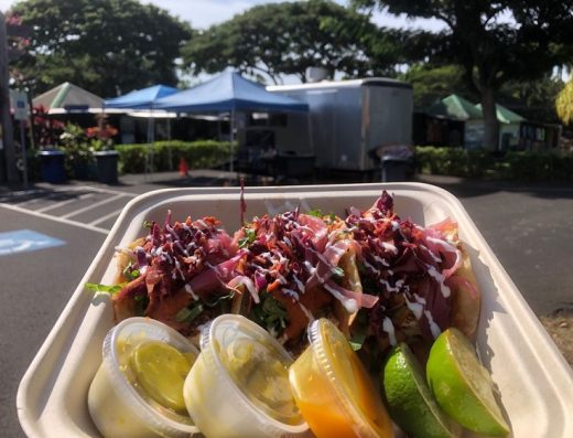 Taco plate held up in front of Shaka Tacoz food truck in Kona, Hawaii