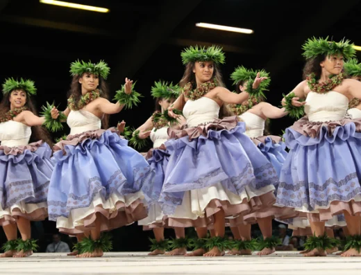 Group of wahine hula dancers performing on stage at the Merrie Monarch Festival in Hilo, Hawaii, celebrating Hawaiian culture through traditional dance.